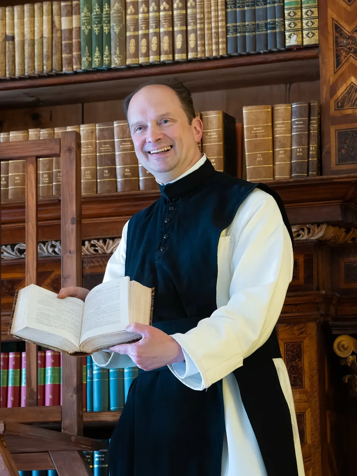 Mann in historischer Kleidung liest ein Buch vor einem Bücherregal