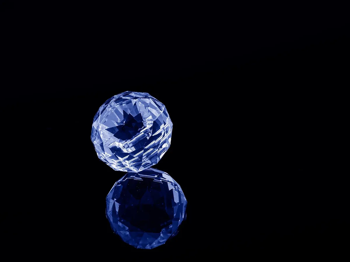 Blaue Glaskugel auf spiegelnder schwarzer Fläche
